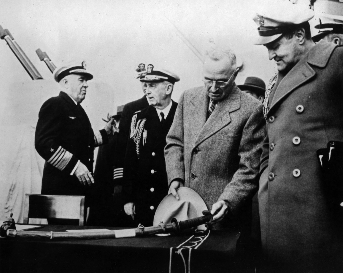 resident Harry S. Truman reviews a Japanese sword on the USS Missouri (BB-63) surrender table, 1945. Naval History and Heritage Command. Public Domain.