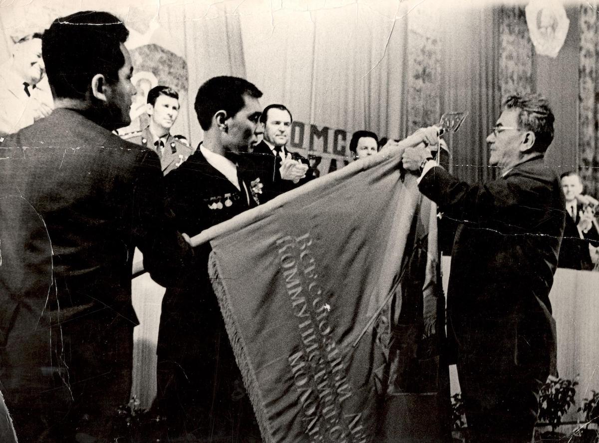 Dinmukhamed Kunaev, First Secretary of the Communist Party of Kazakhstan, awarding a Soviet Army unit's battle flag, 1986. EgemenMedia (CC BY-SA 4.0).