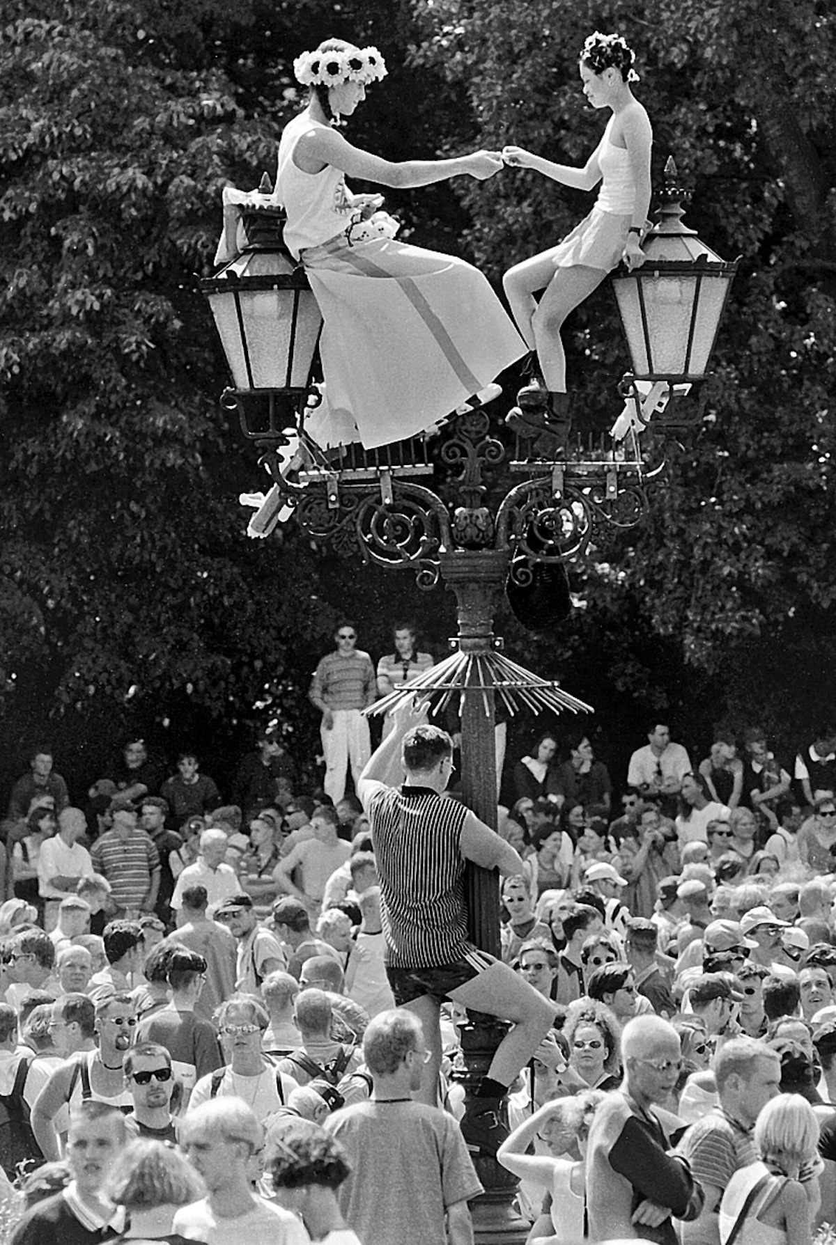 Revellers sit atop a street lamp during the Love Parade, by Gerd Danigel, 1997. Deutsche Fotothek. Public Domain.