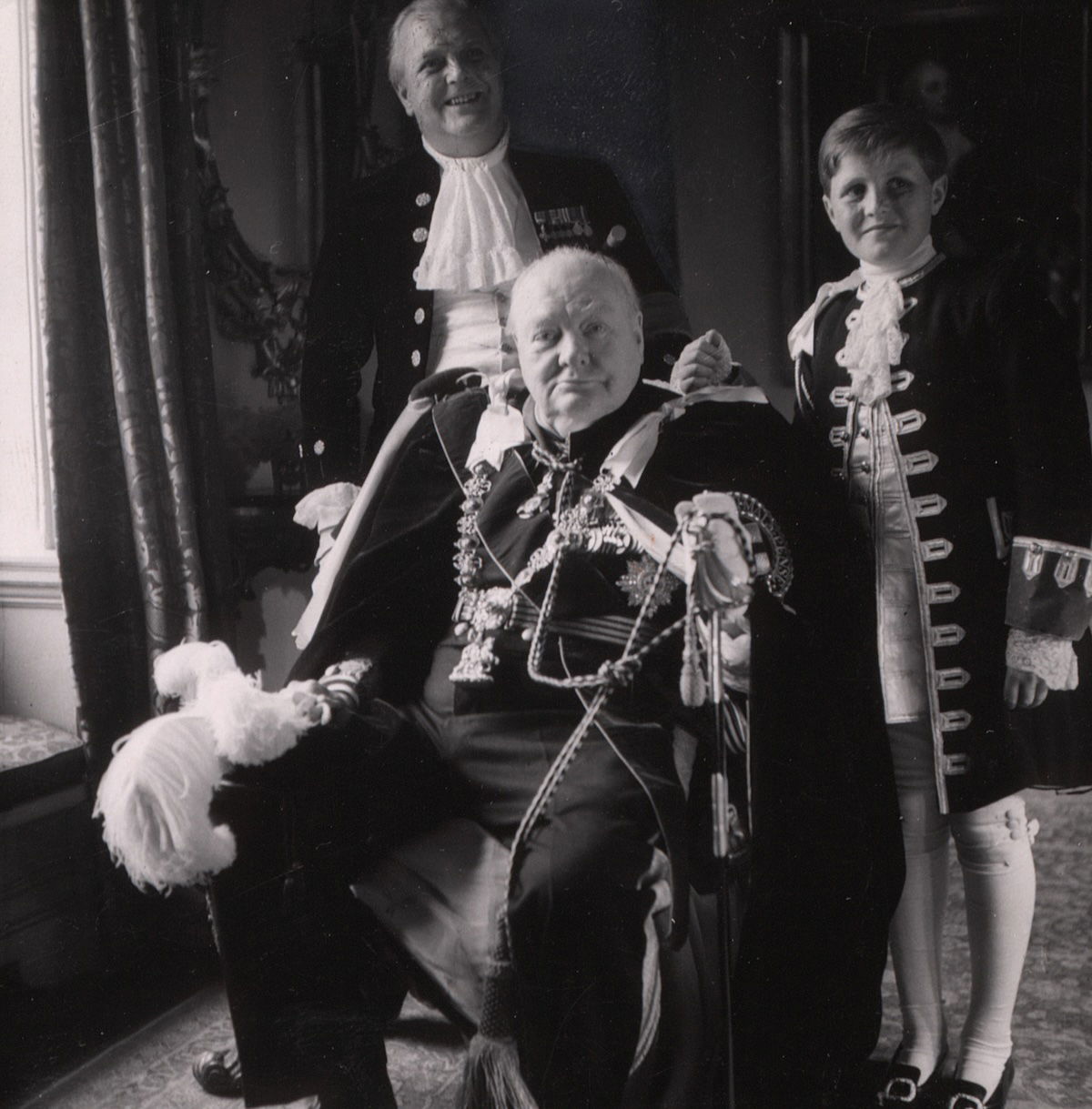 Sir Winston, his son Randolph, and grandson, Winston in coronation robes, by Toni Frissell, June 1953. Library of Congress. Public Domain.