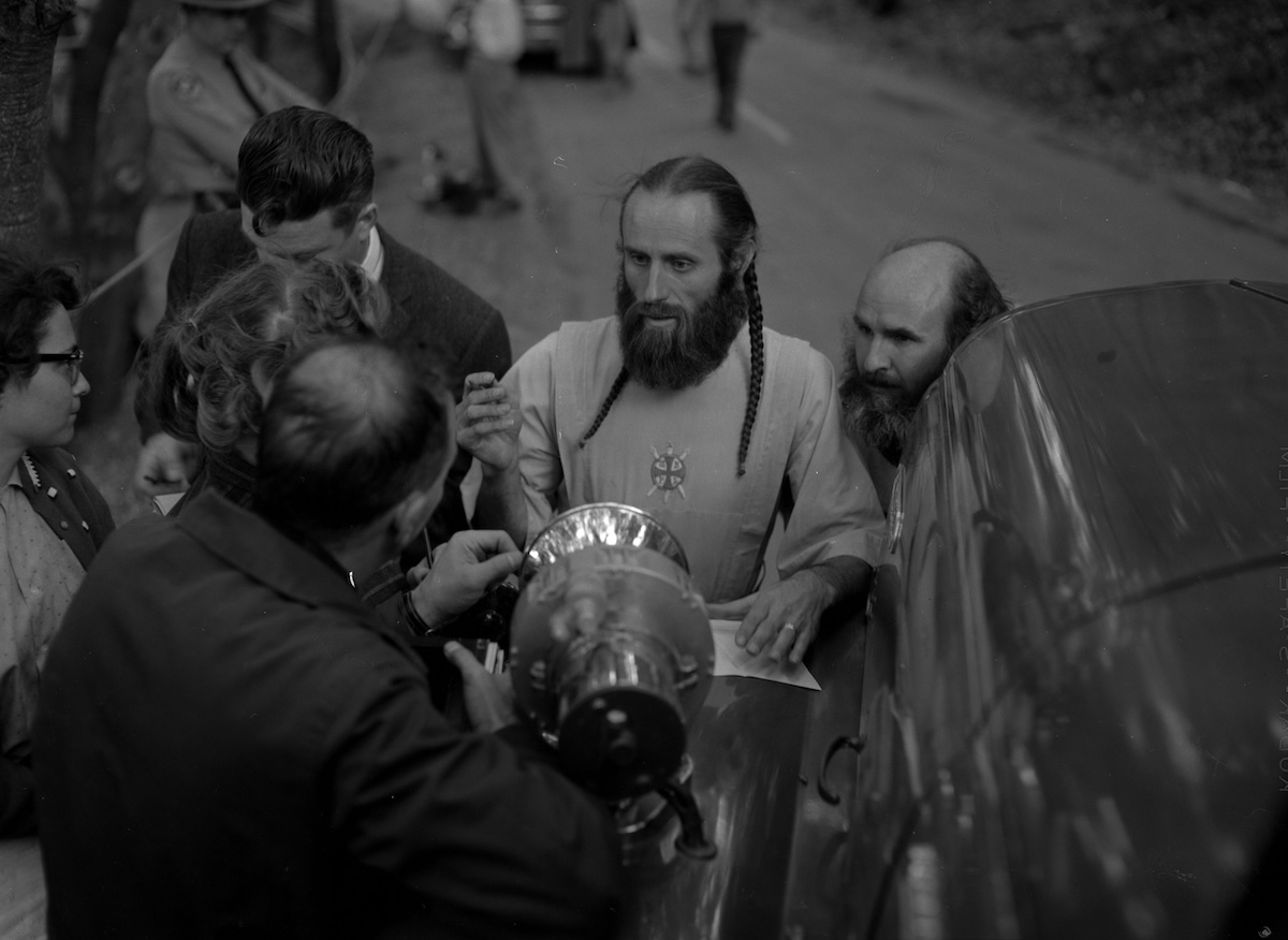 Bishop Asaiah talks with police and reporters outside the ruins of the headquarters of the Fountain of the World cult following an bomb attack by two former members, 11 December 1958. The Regents of the University of California (CC BY 4.0