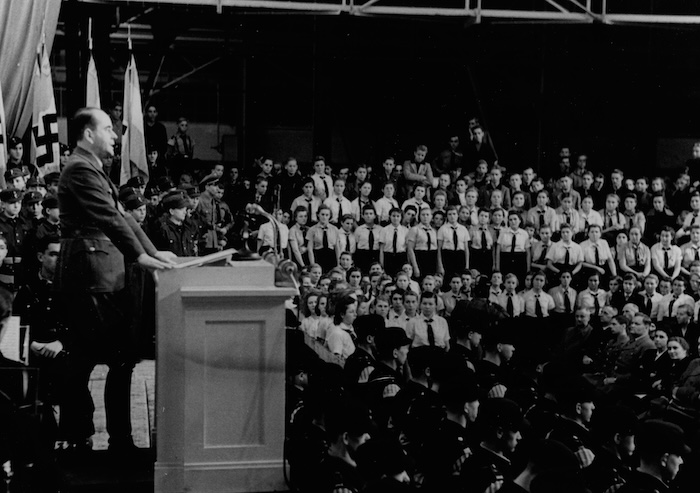 Minister of the Armaments Albert Speer speaks to a gathering of Hitlerjugend and Bund Deutscher Mädel, c. 1943. Narodowe Archiwum Cyfrowe. Public Domain.