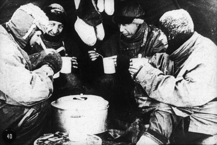 Evans, Bowers, Wilson and Scott at mealtime in their tent, by Herbert Ponting, 1912. Australian National Maritime Museum. Public Domain.