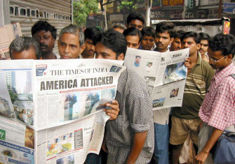 Passengers waiting at a bus-stop read details of the terrorists attacks on Washington and New York in newspapers in the eastern Indian city of Calcutta on September 12, 2001