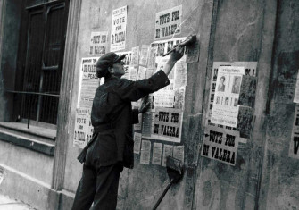 A man pastes over ‘Vote for de Valera’ election posters with arrest notices, Ireland, c.1923. 